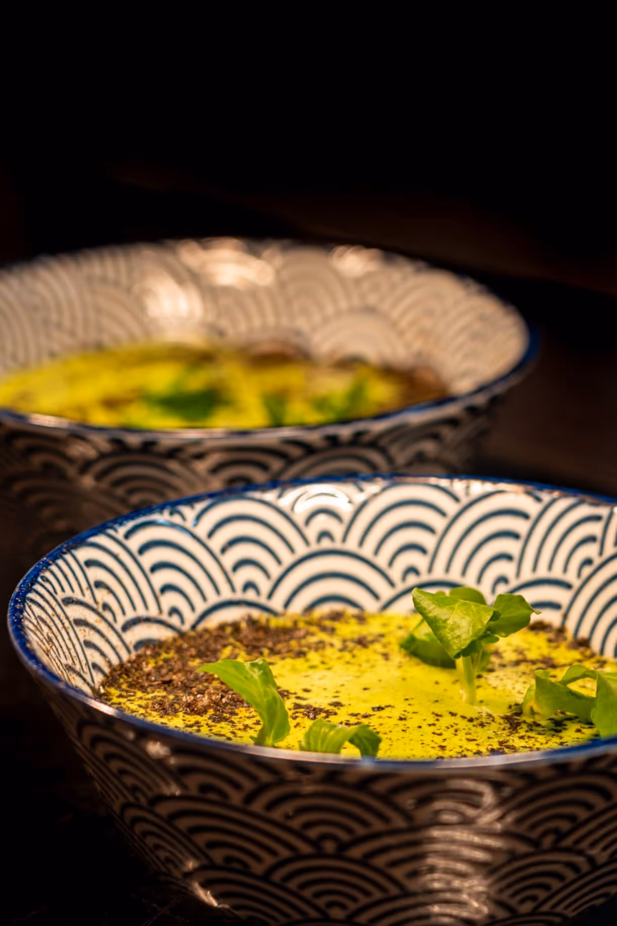 Zwei gemusterte Schüsseln mit buttrig, zart gebratenen Kabeljaubäckchen, Espuma aus Brunnenkresse und Nori-Staub im Nashi Dining in Erfurt.