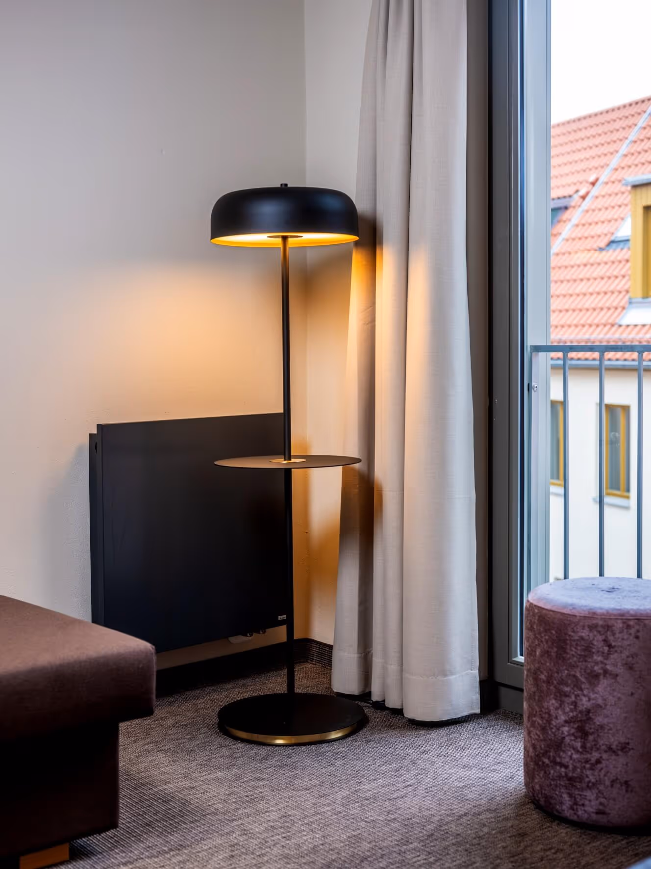 Moderne schwarze Stehlampe in der Junior-Suite vom Nashi Rooms Hotel in Erfurt, mit einem Fenster mit Blick auf die Dächer der Erfurter Altstadt.