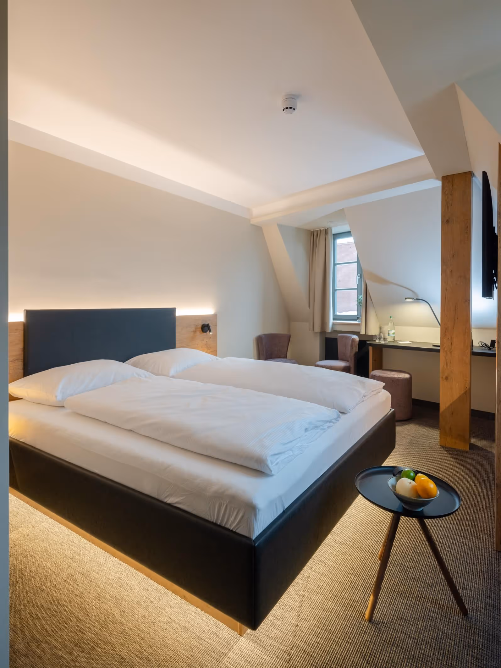 Modernes Hotelzimmer im japanischen Stil mit Doppelbett, Schreibtisch, Stühlen und Fenster mit Blick auf die Krämerbrücke - Nashi Rooms Hotel im Zentrum von Erfurt.