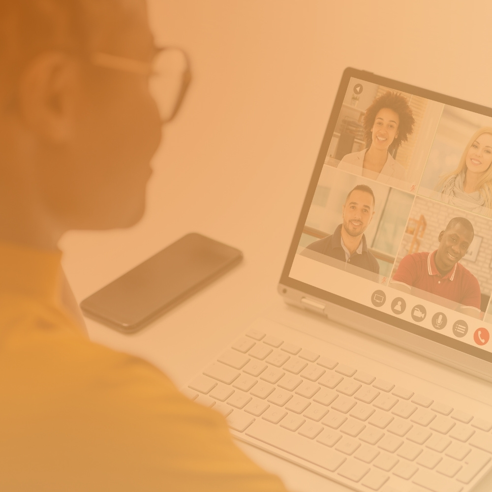 Person attending a video conference call with four smiling participants on a laptop screen.