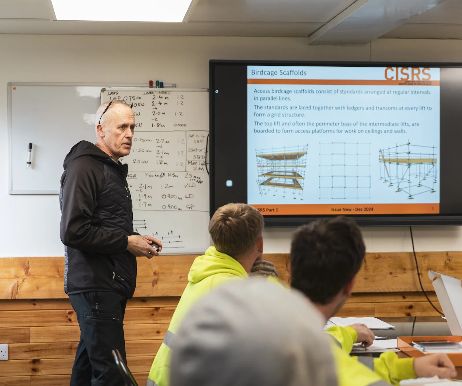 Instructor explaining birdcage scaffolds using a screen presentation to students in a classroom setting.
