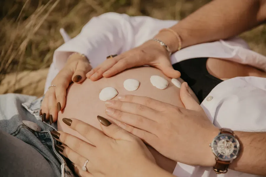 Photographe maternité Loire-Atlantique — détails du ventre de femme enceinte avec des coquillages et les mains posées dessus