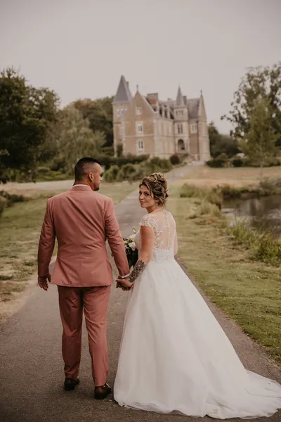 Photographe mariage Loire-Atlantique — mariés marchant dans une allée vers un château