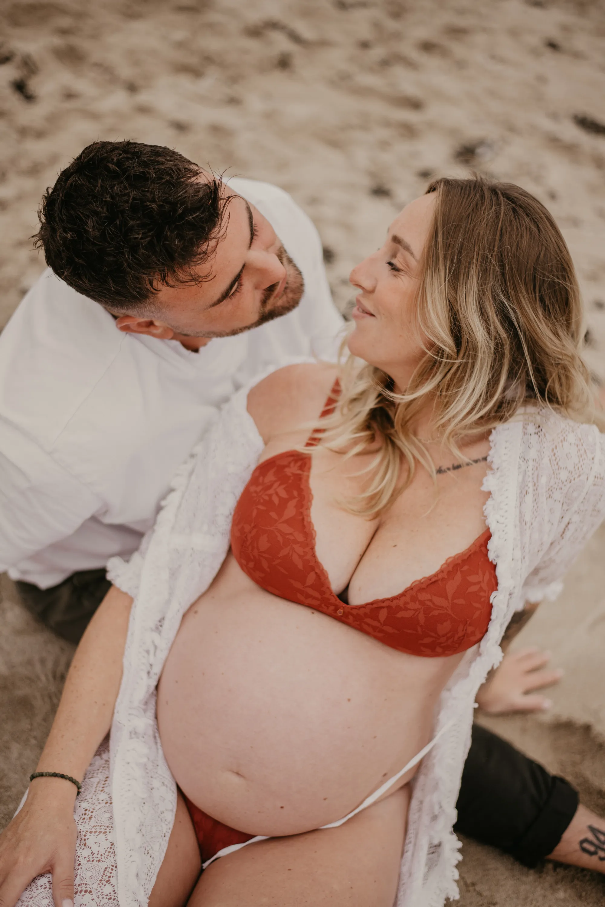 Photographe maternité Loire-Atlantique — couple femme enceinte assis sur le sable se regardant dans les yeux