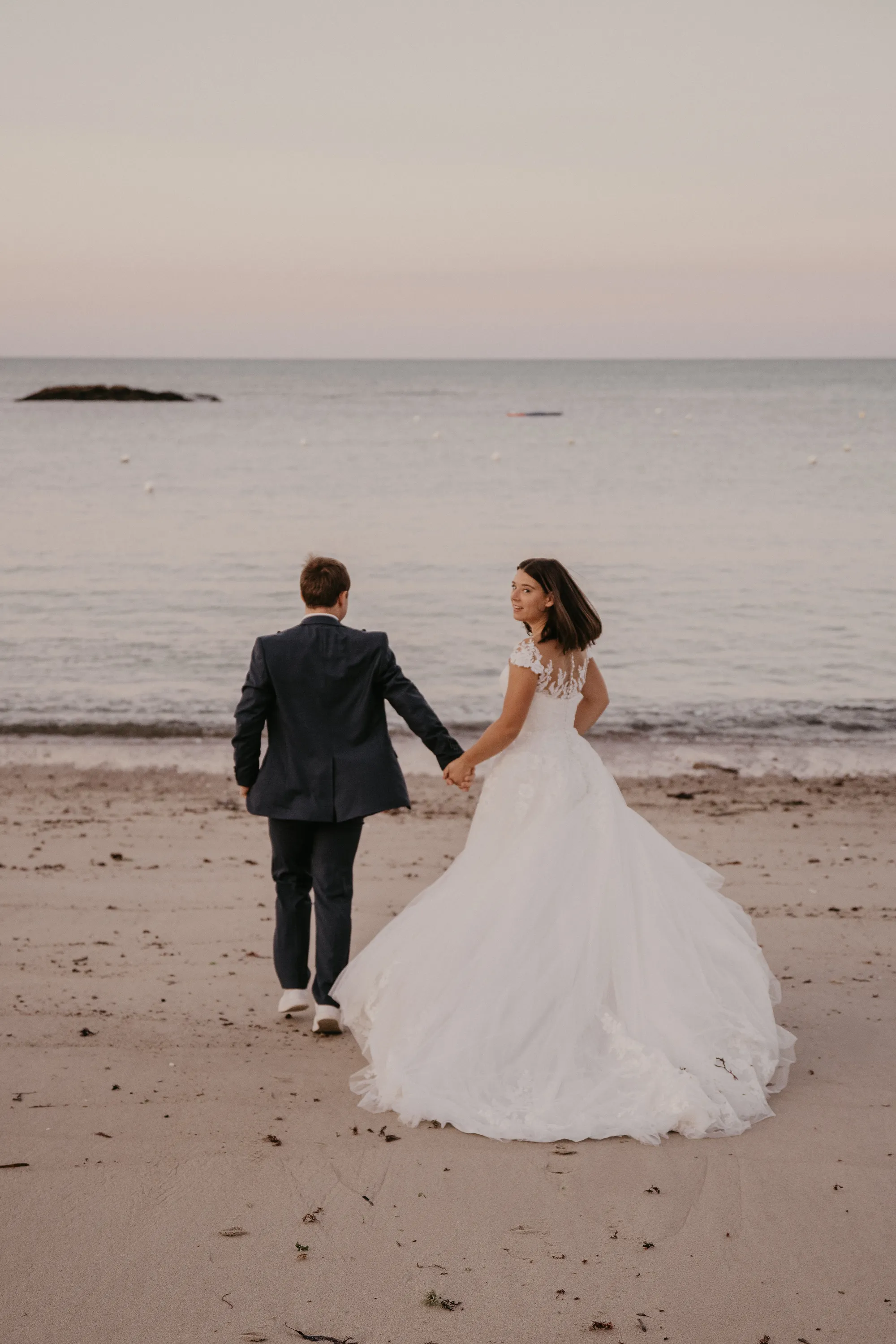 Photographe mariage Loire-Atlantique — mariés de dos marchant au bord de la mer