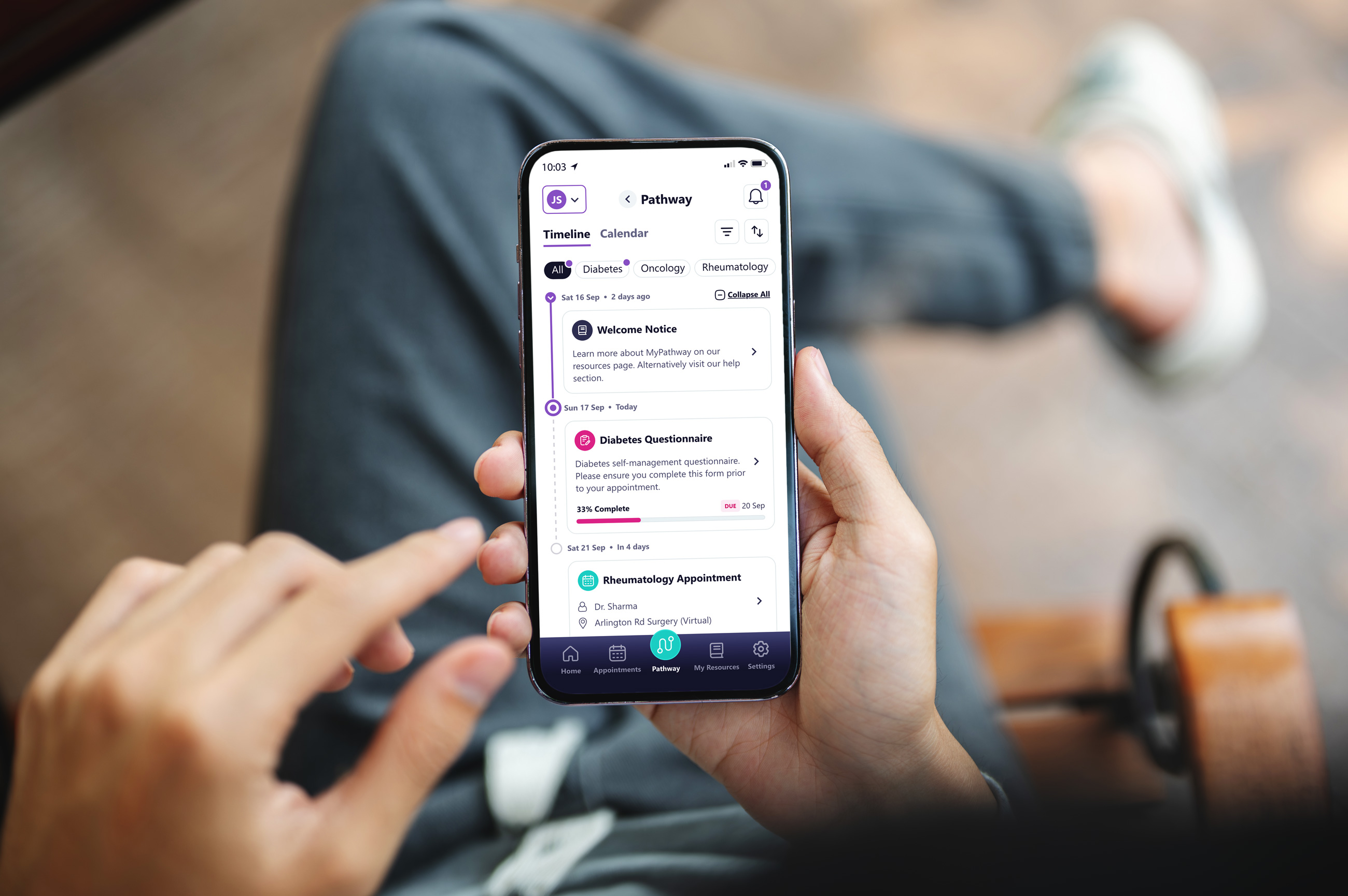 Person holding a phone showing a healthcare app with diabetes and rheumatology appointments.