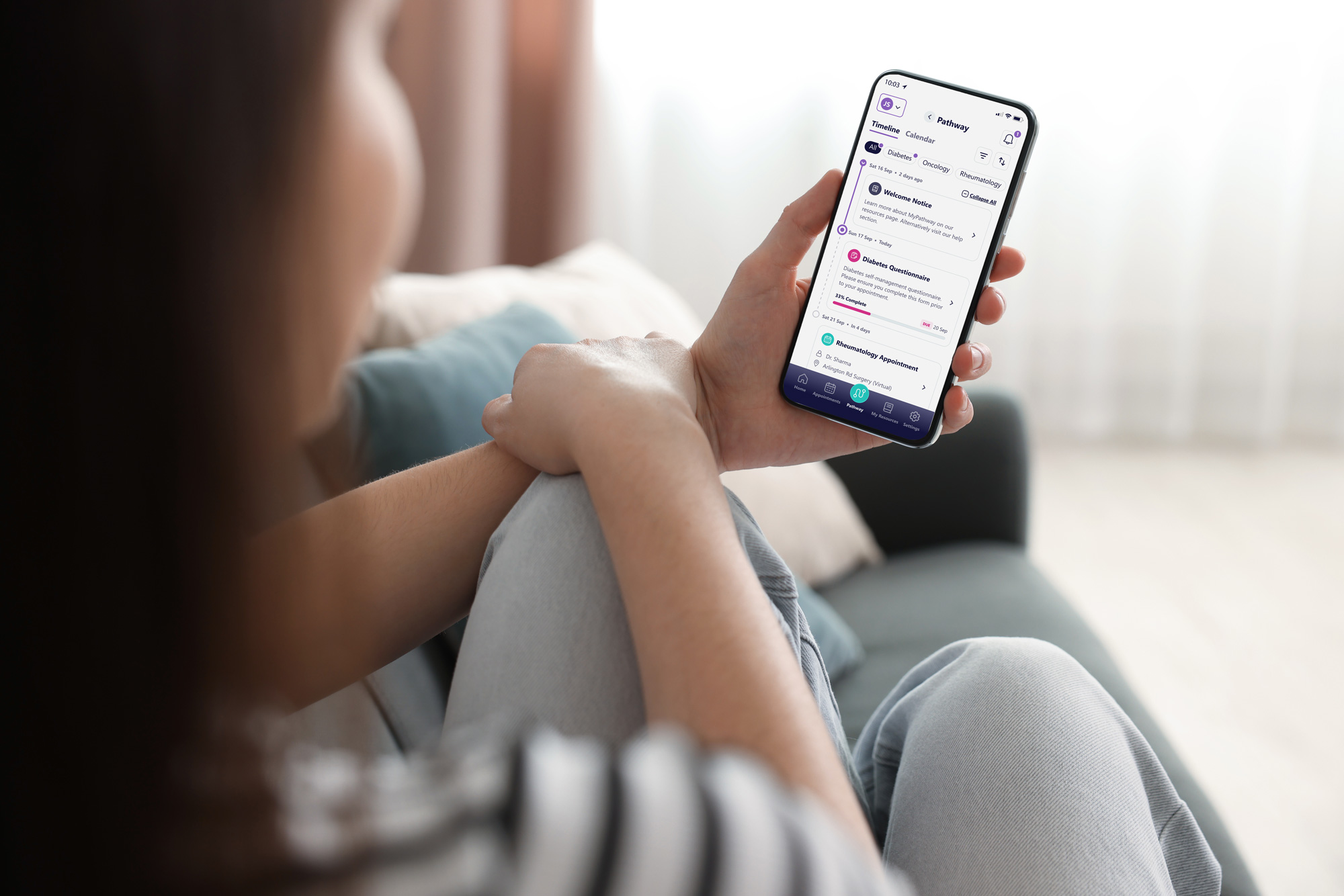 Person holding smartphone displaying a health app with appointment and questionnaire details.