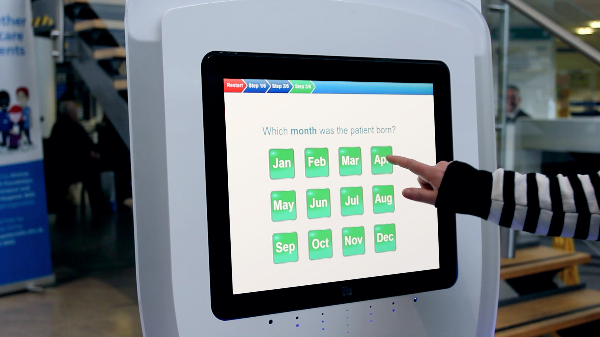 Hand pointing to April on touchscreen asking which month the patient was born.