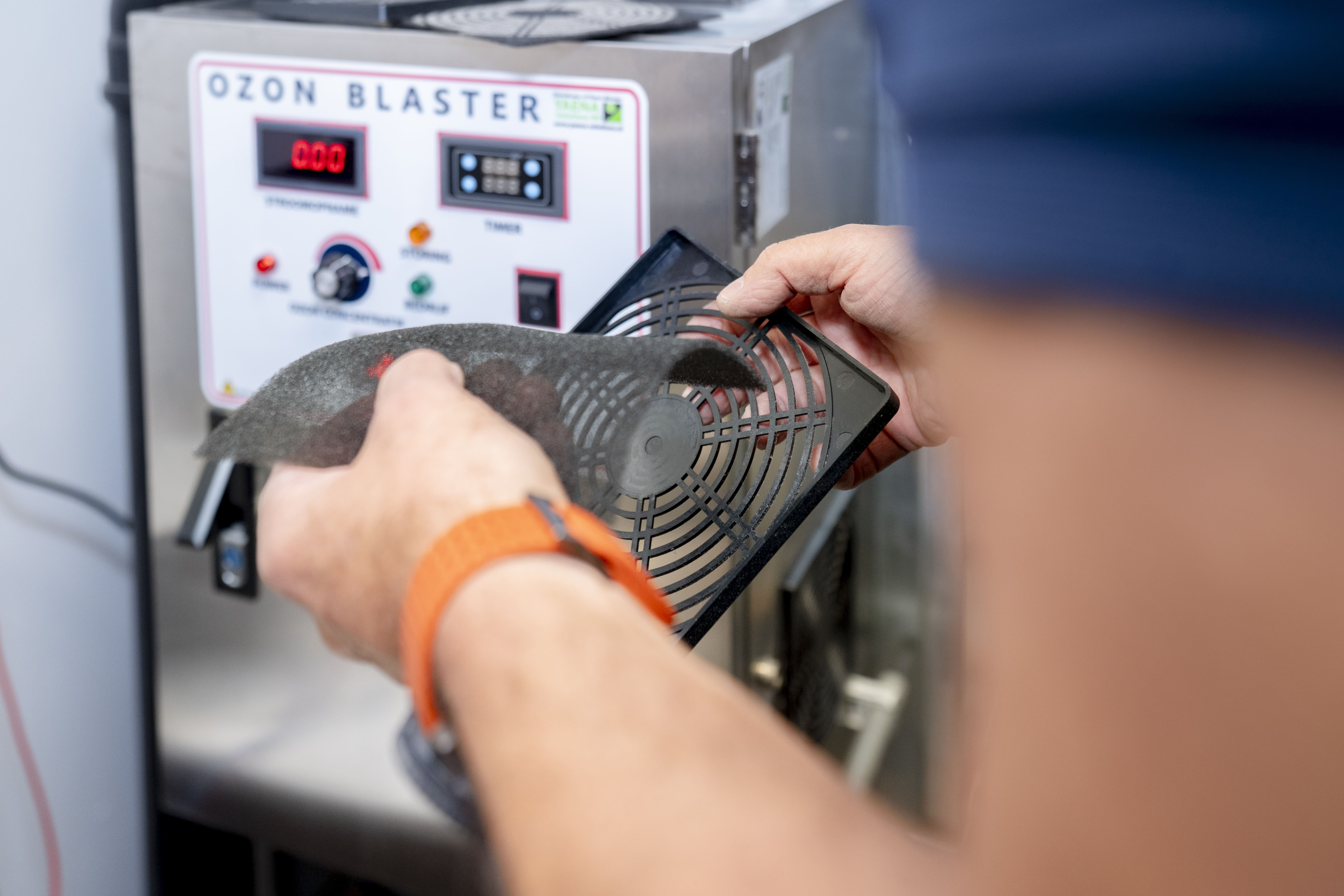 Persoon verwijdert of plaatst een filter op een rooster van een ozonblaster machine.
