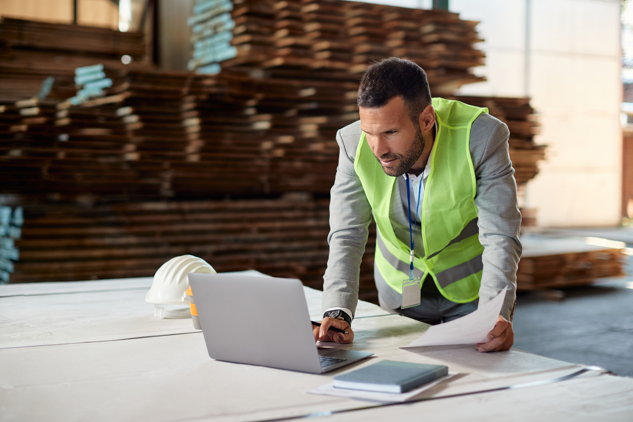 Responsable administratif DRS Energie consultant un ordinateur portable dans un entrepôt logistique