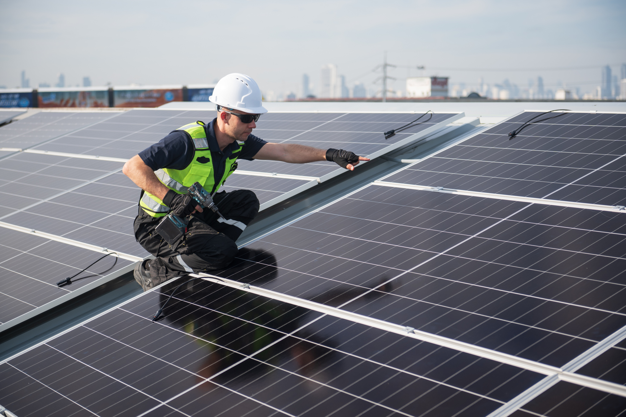Technicien DRS Energie installant des panneaux photovoltaïques sur toiture plate en milieu urbain