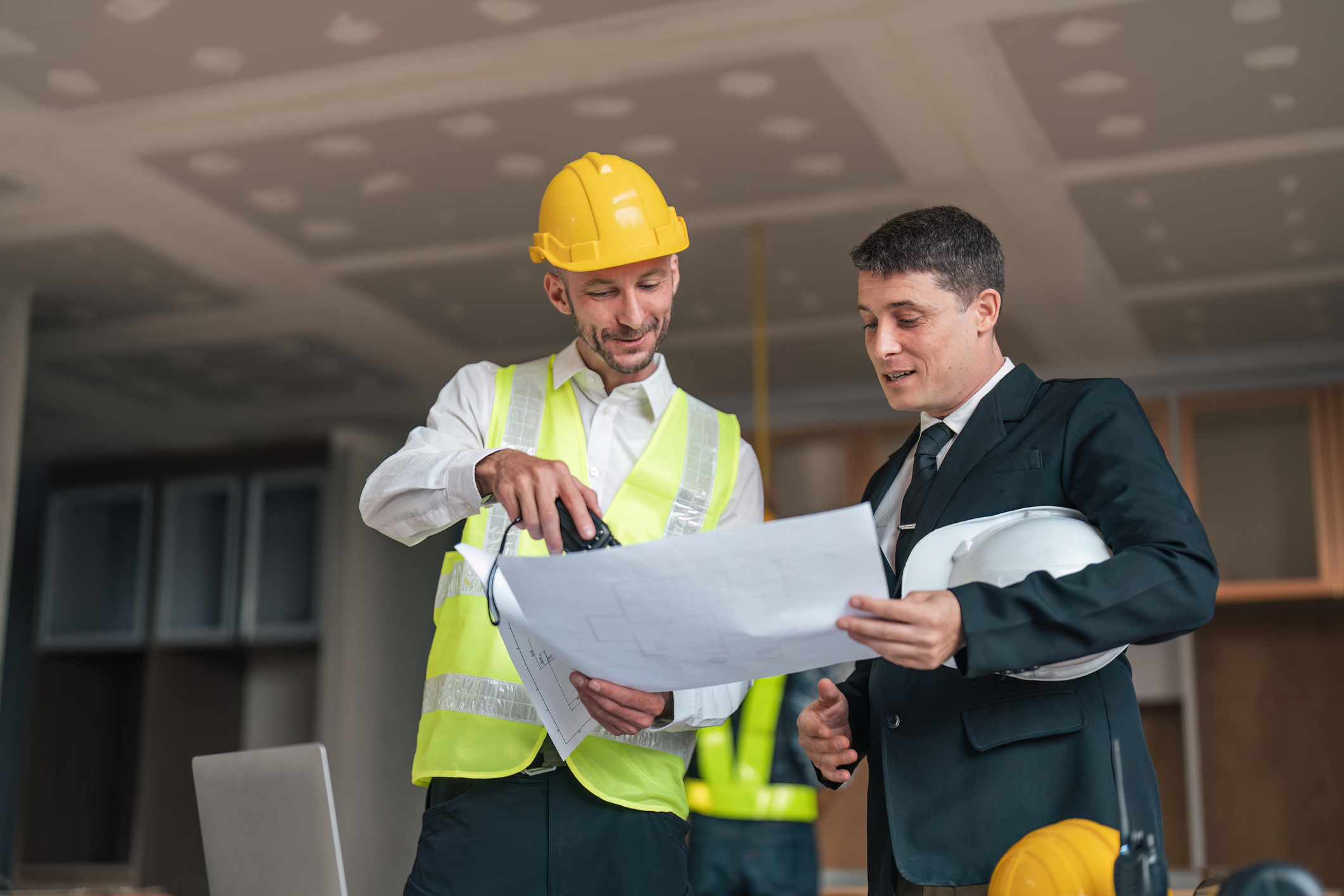 Chef de projet DRS Energie présentant des plans techniques à un client lors d'une réunion sur chantier