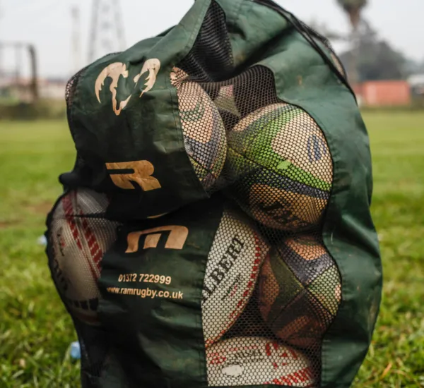 A large bag of rugby balls on a pitch