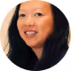 Smiling Asian woman with long black hair against a light background.