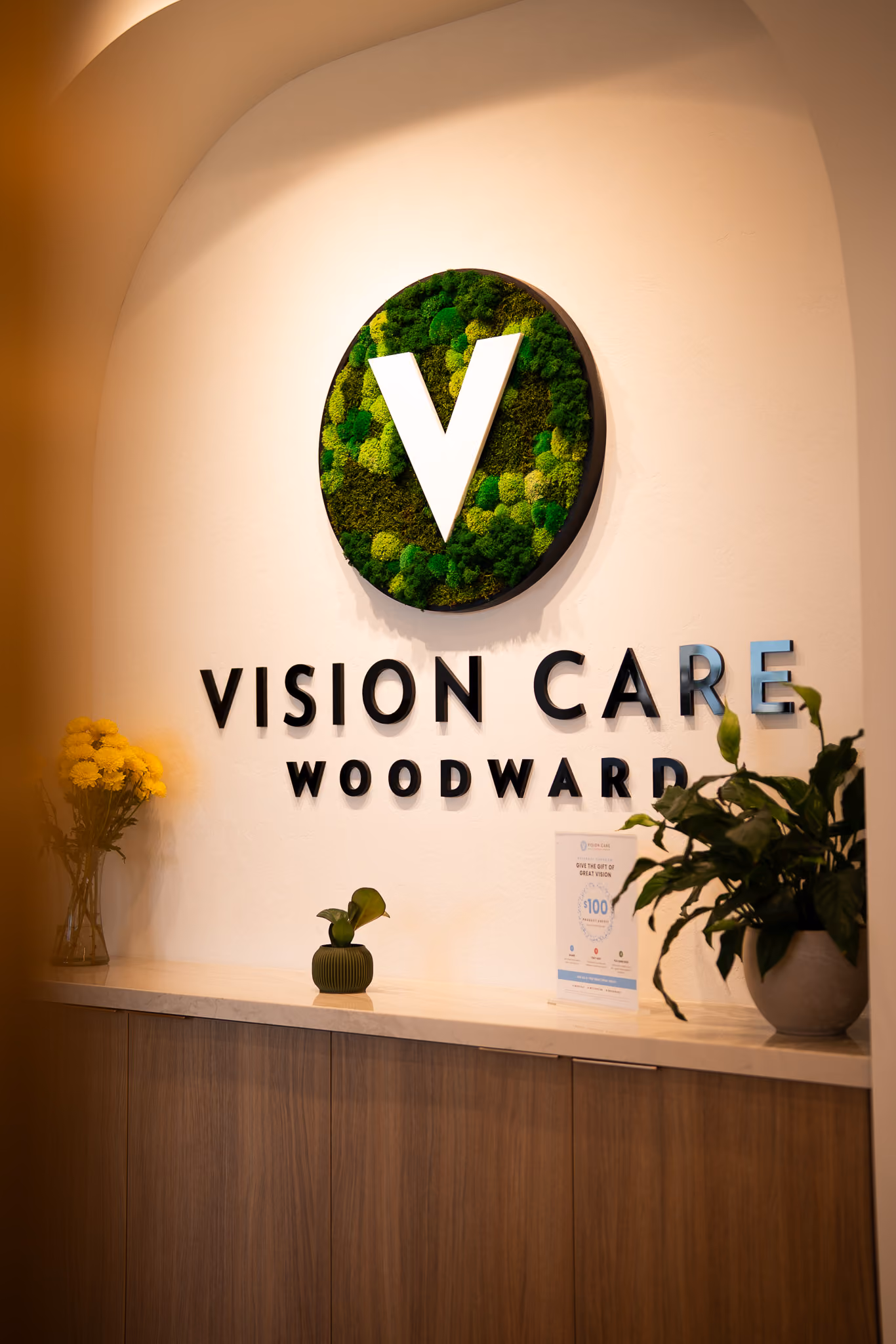Vision Care Woodward logo mounted on a wood-slatted feature wall in the clinic.