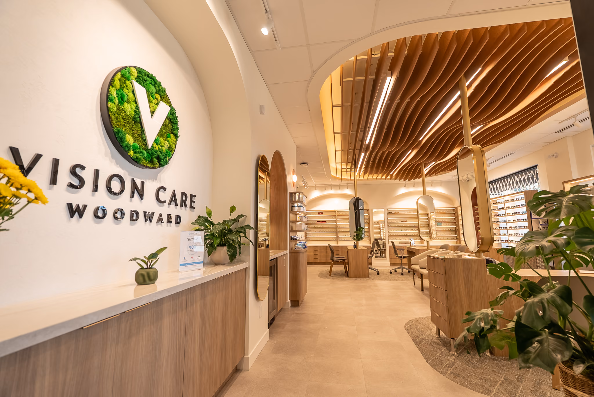 Interior of the Vision Care Woodward clinic showing the optical showroom with eyewear displays and a wood-slatted ceiling.