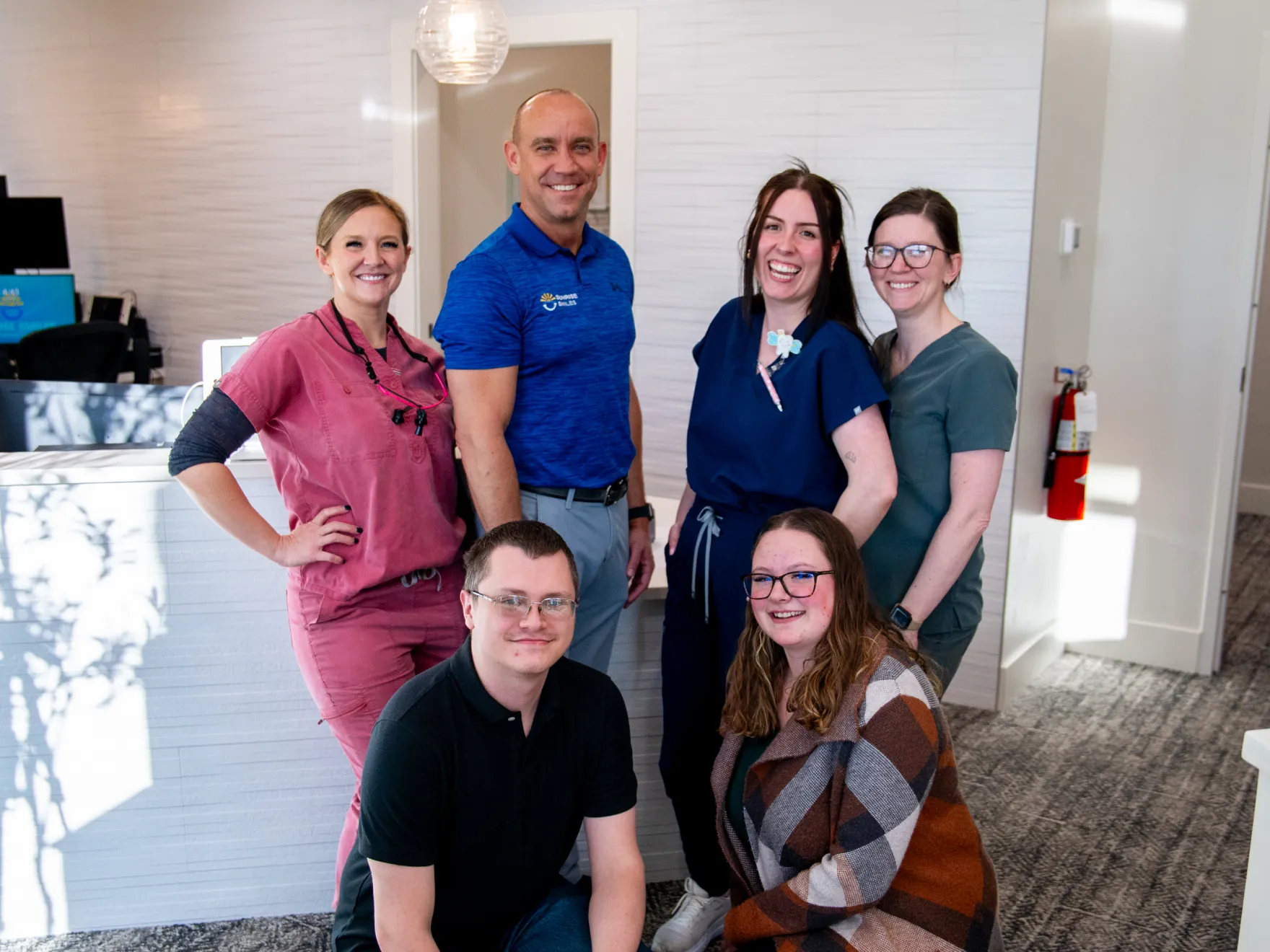 Group of six smiling healthcare professionals posing in a medical office.