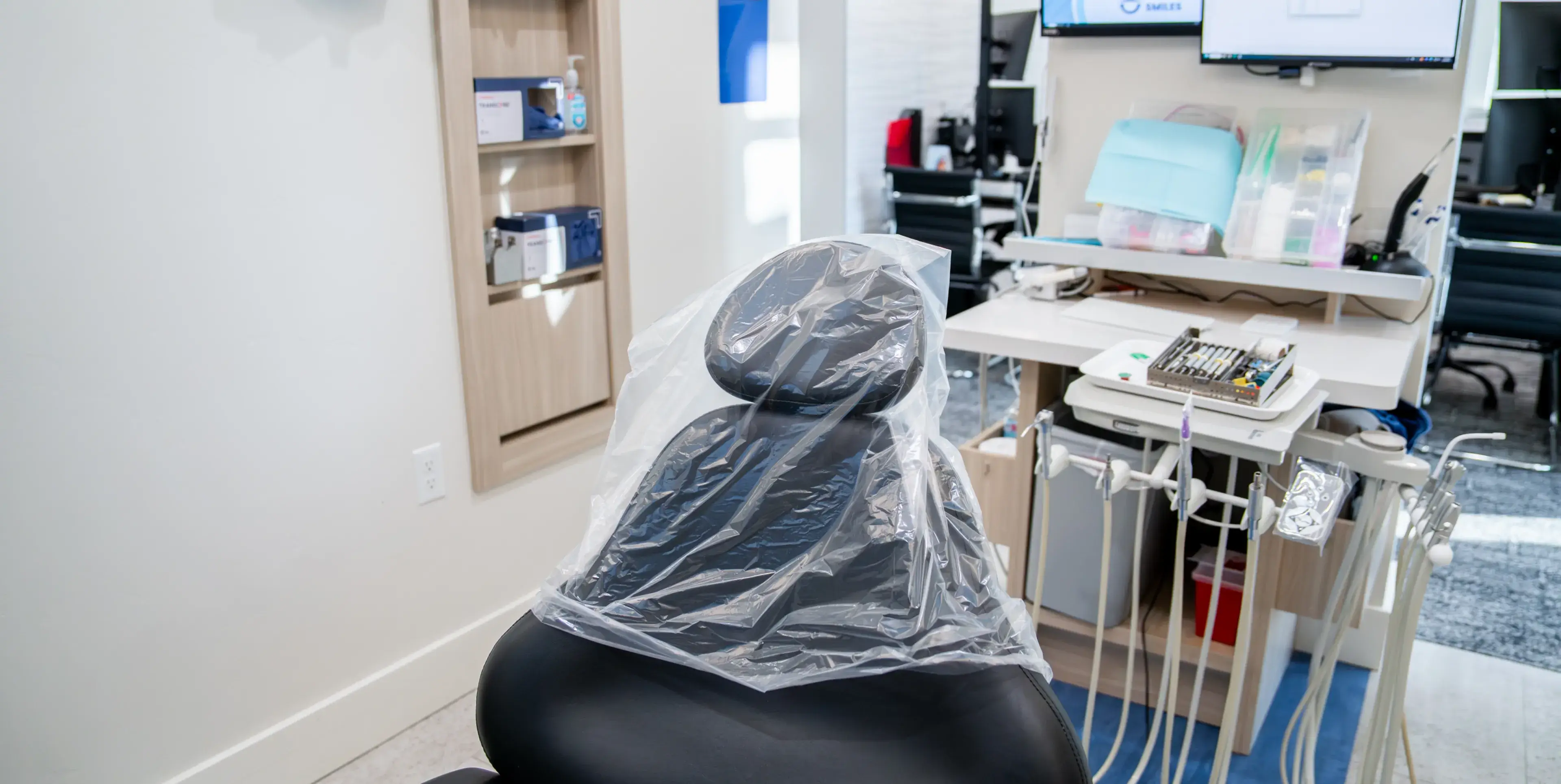 Dental examination chair covered with clear plastic in a clean dental clinic room.