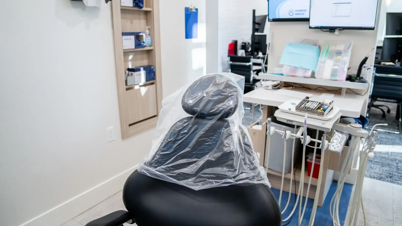 Close-up of a black dental chair covered with a clear plastic protective cover in a modern dental office.