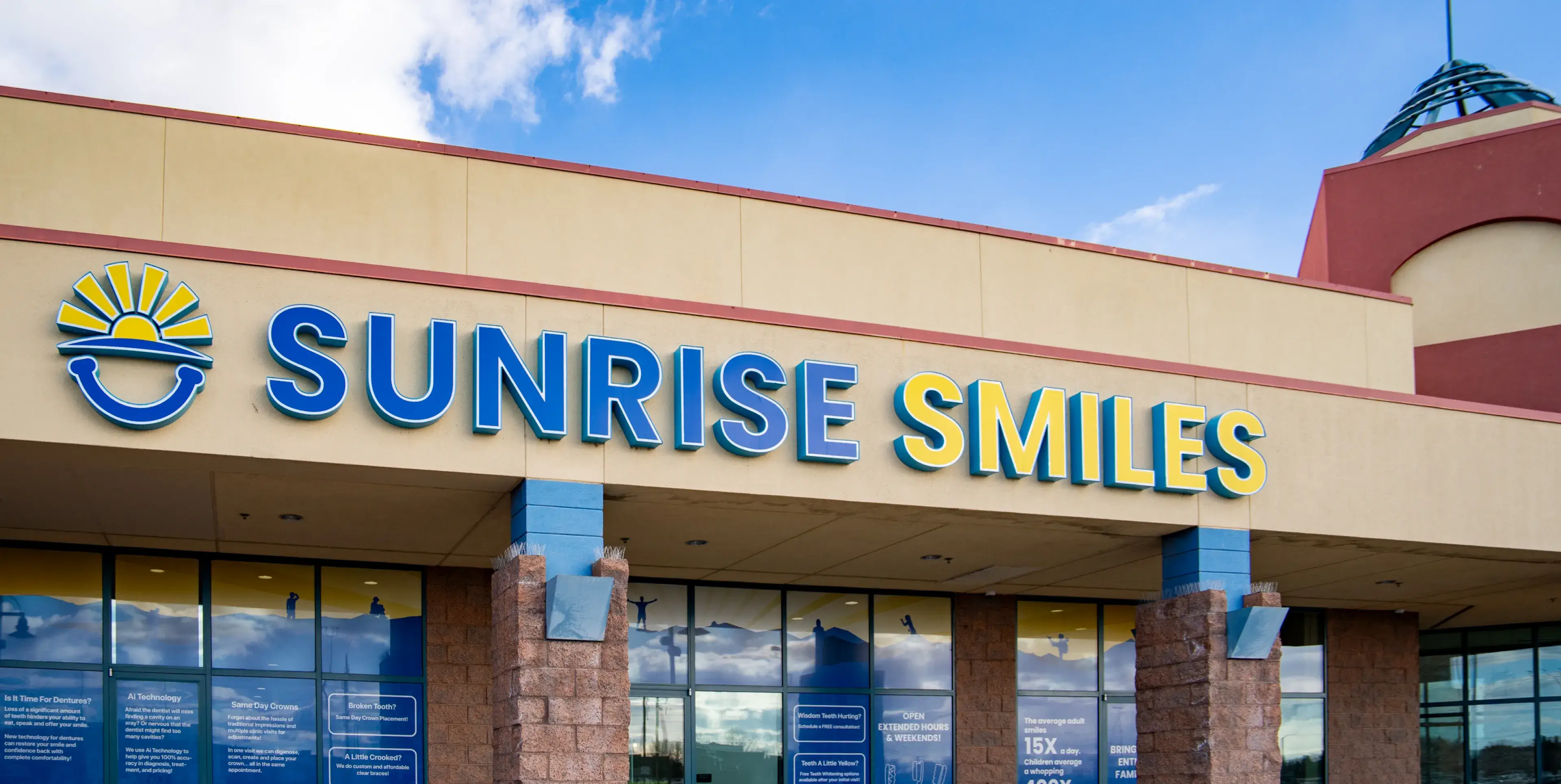 Exterior of Sunrise Smiles dental office with blue and yellow sign above entrance.