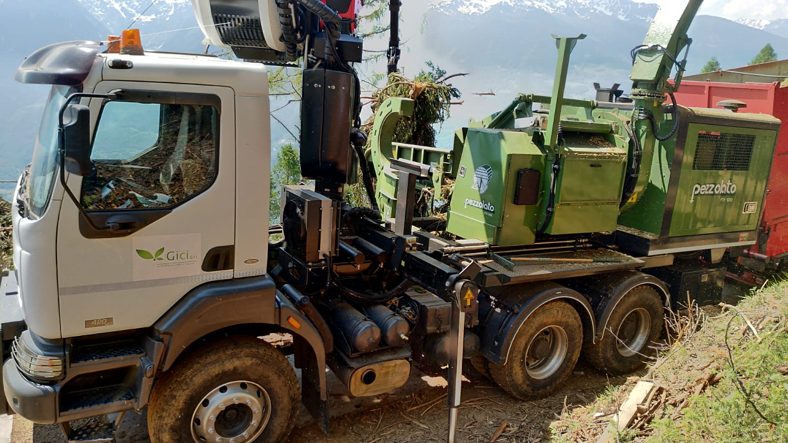 White truck with green Pezzolato wood chipping machine loaded on its back in a mountainous outdoor area.