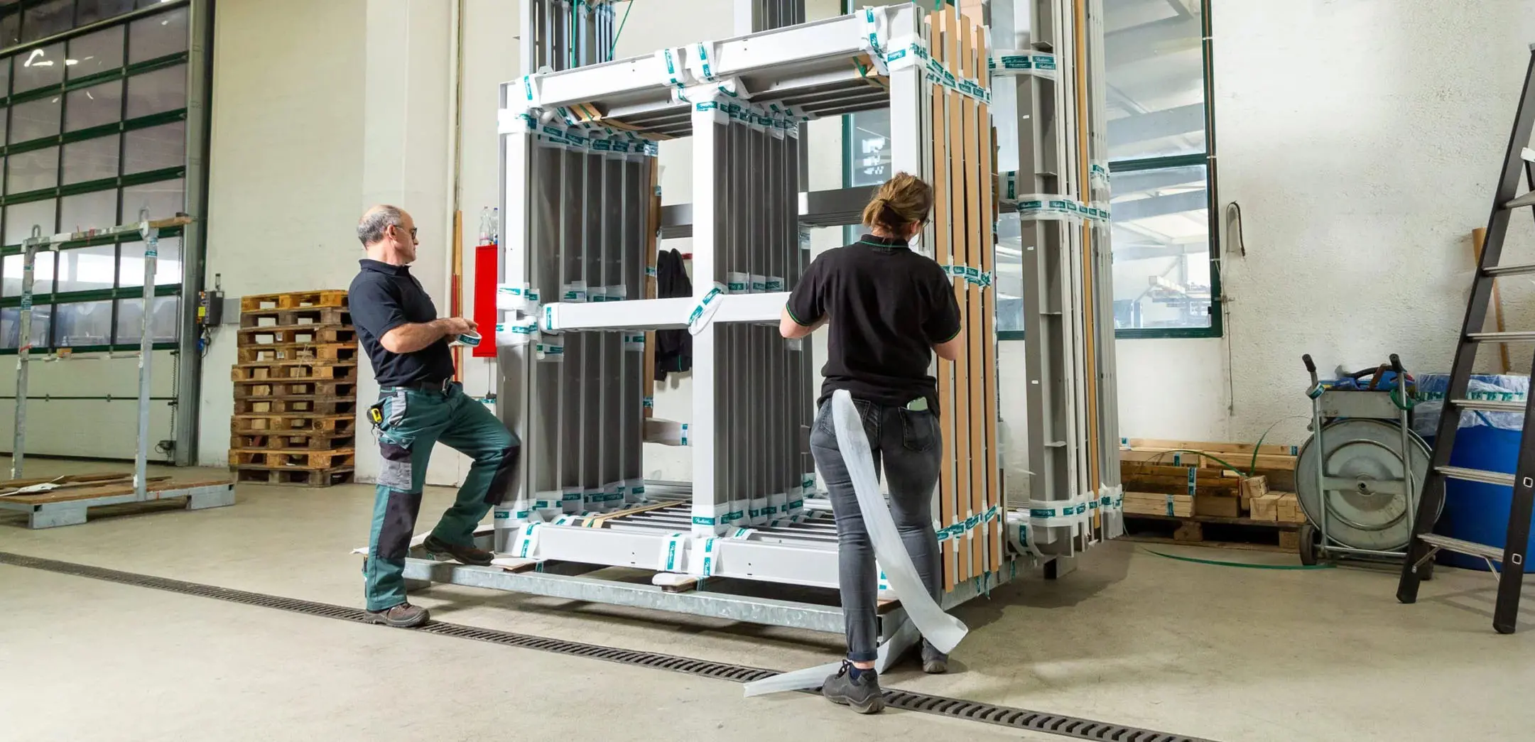 Mitarbeitende verpacken Aluminiumprofile fachgerecht für den sicheren Transport nach geprüften QUALICOAT Qualitätsstandards.