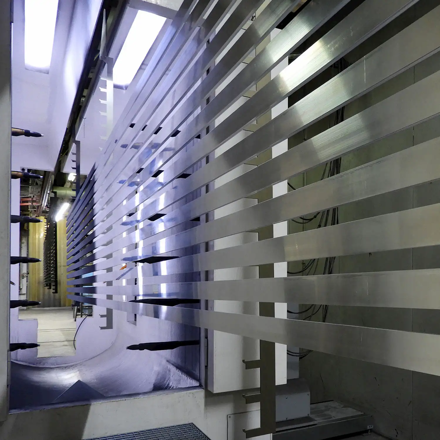 Aluminiumprofile in automatisierter Pulverbeschichtungsanlage während des Veredelungsprozesses, präzise Oberflächenbehandlung für dauerhaften Korrosionsschutz.