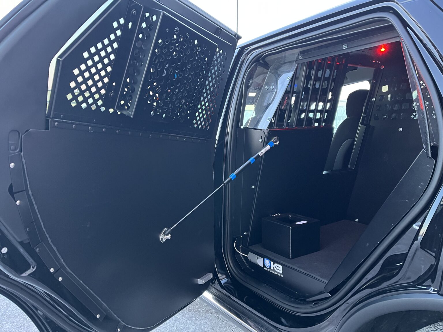 Interior of a police vehicle's rear compartment with protective bars and partition installed.