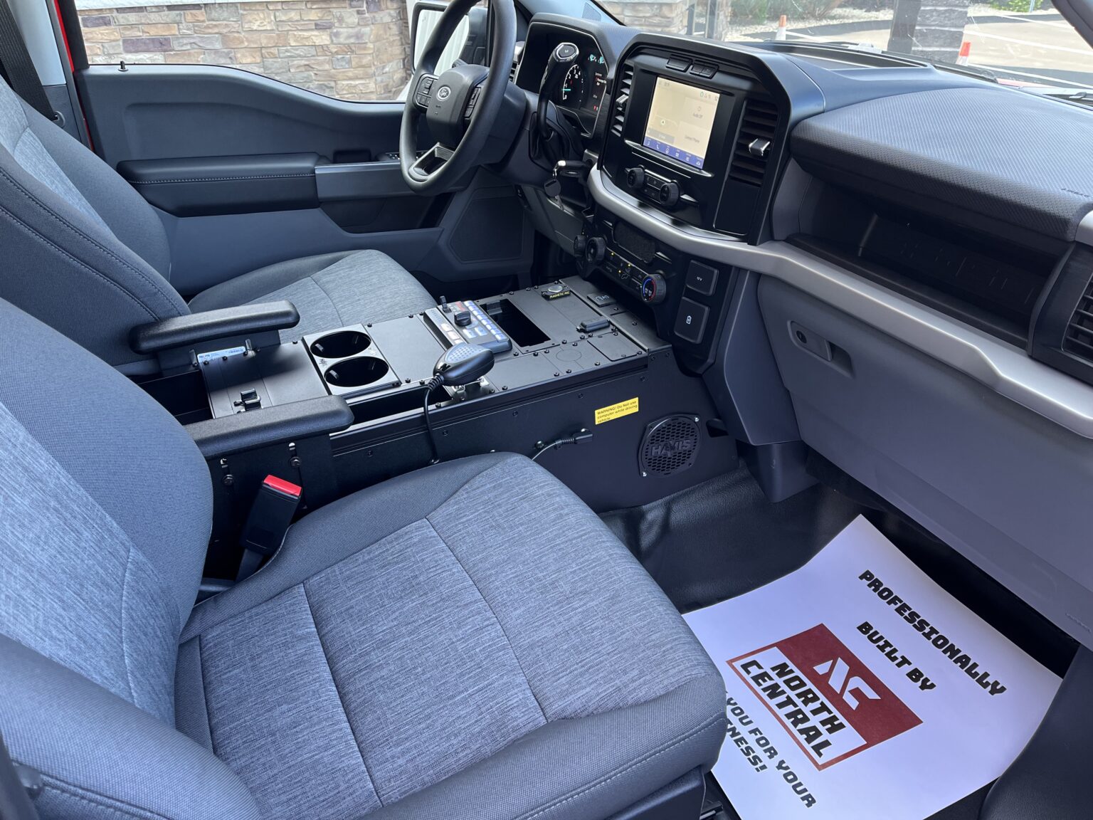 Interior of a vehicle showing front seats, center console with radio, and dashboard with touchscreen display.