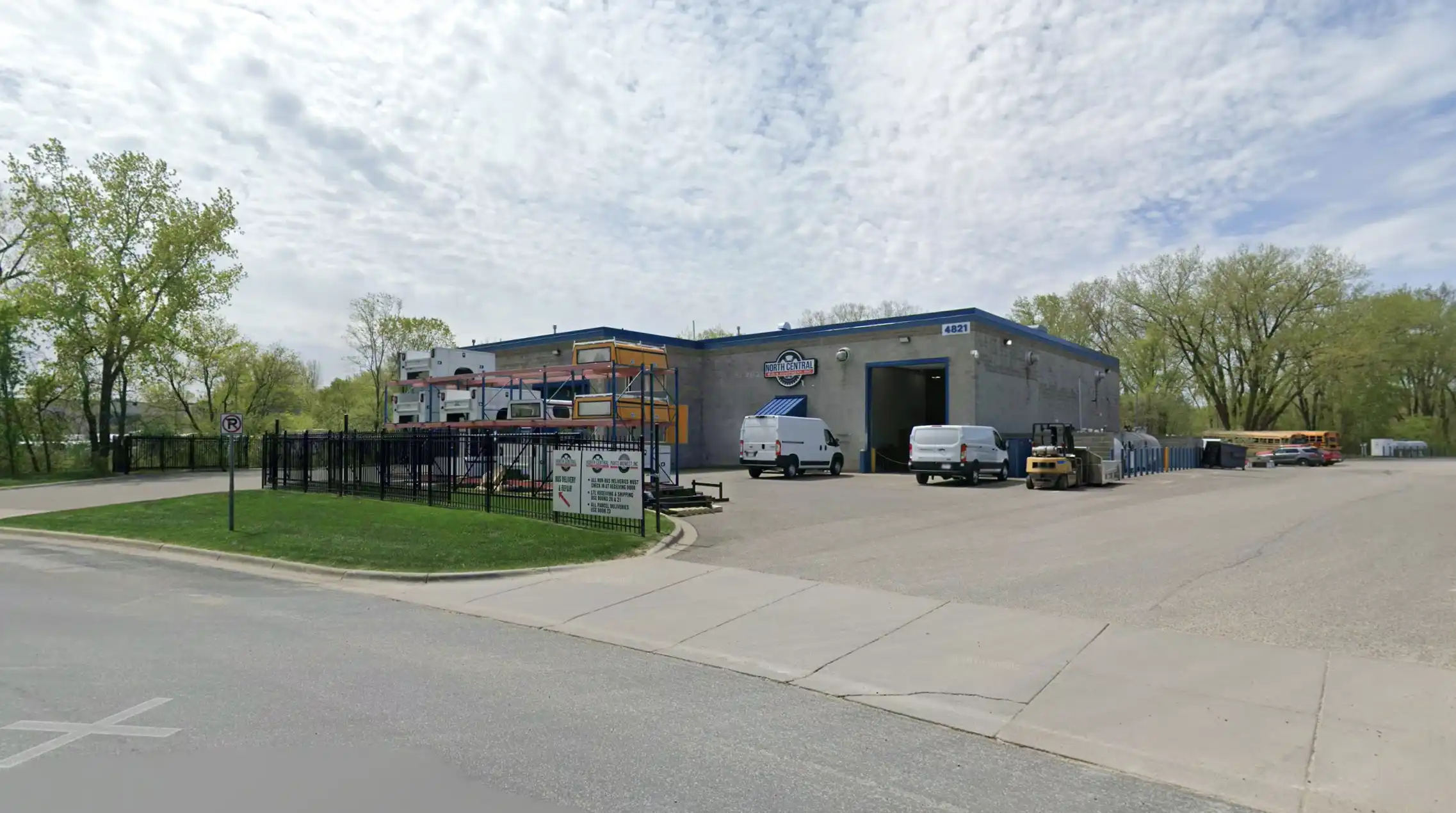Industrial building with North Central sign, two white vans, forklift, and parked vehicles outside.