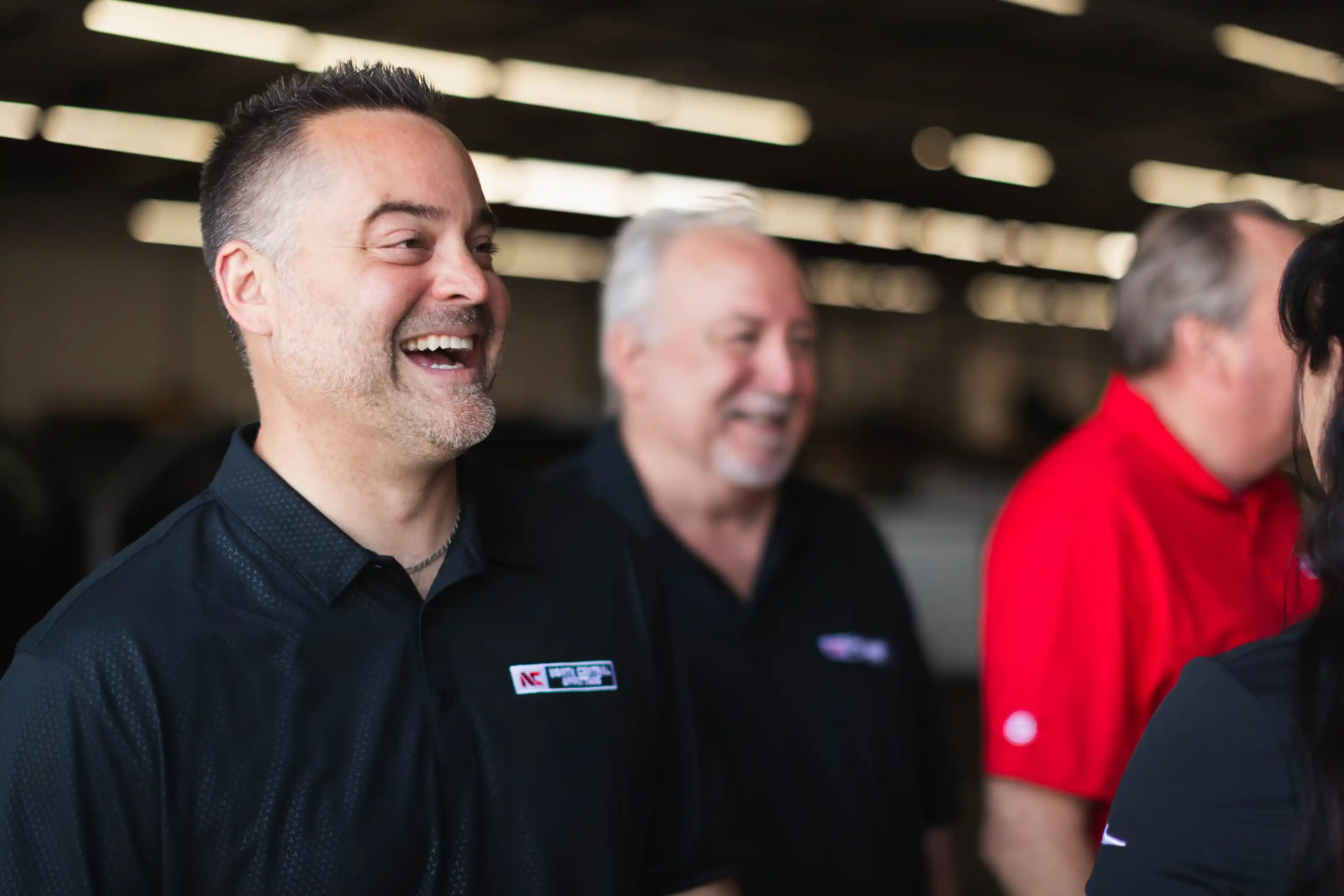 Group of four adults smiling and talking in a brightly lit indoor space.