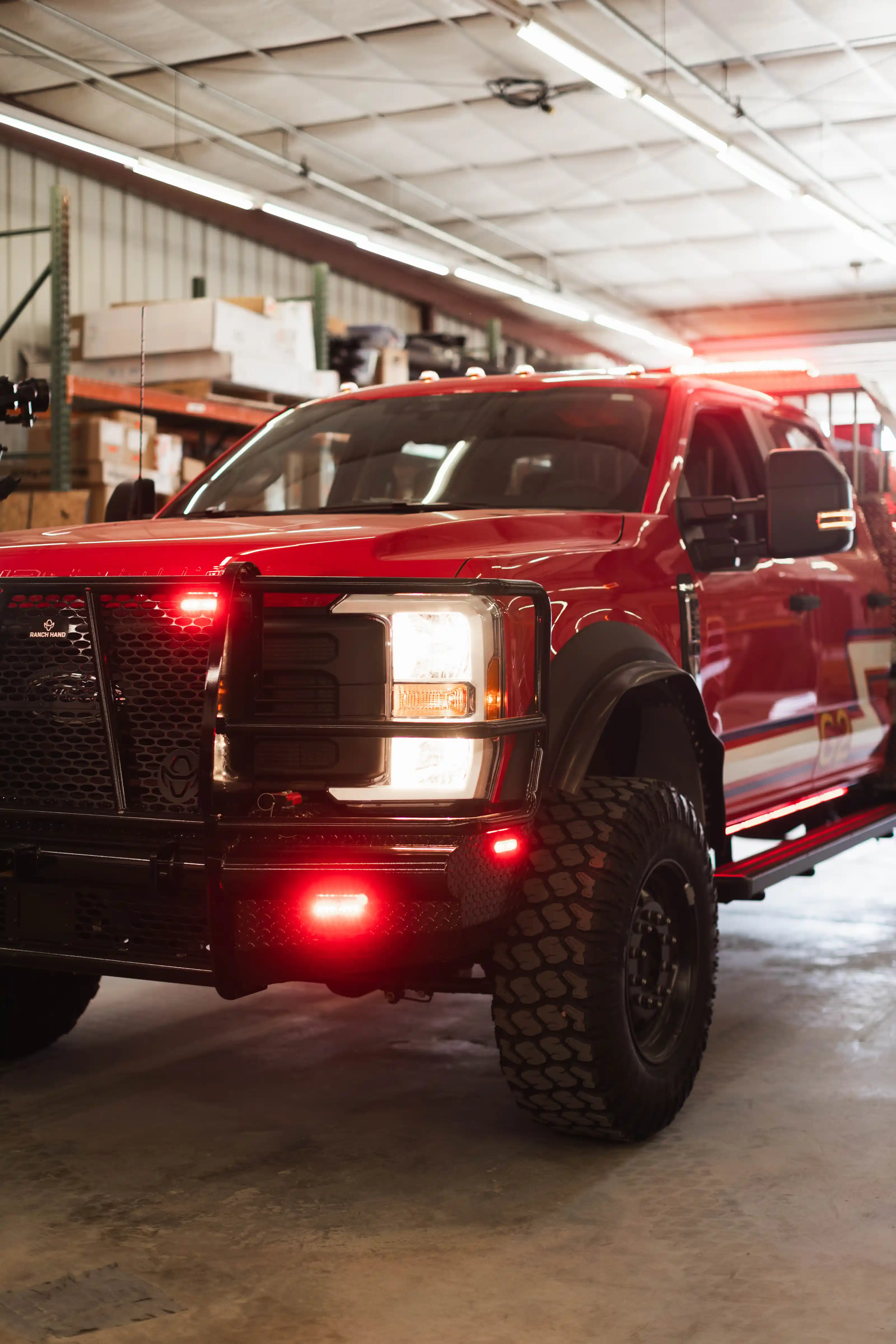 Front view of a red emergency truck with lights on, parked inside a warehouse.
