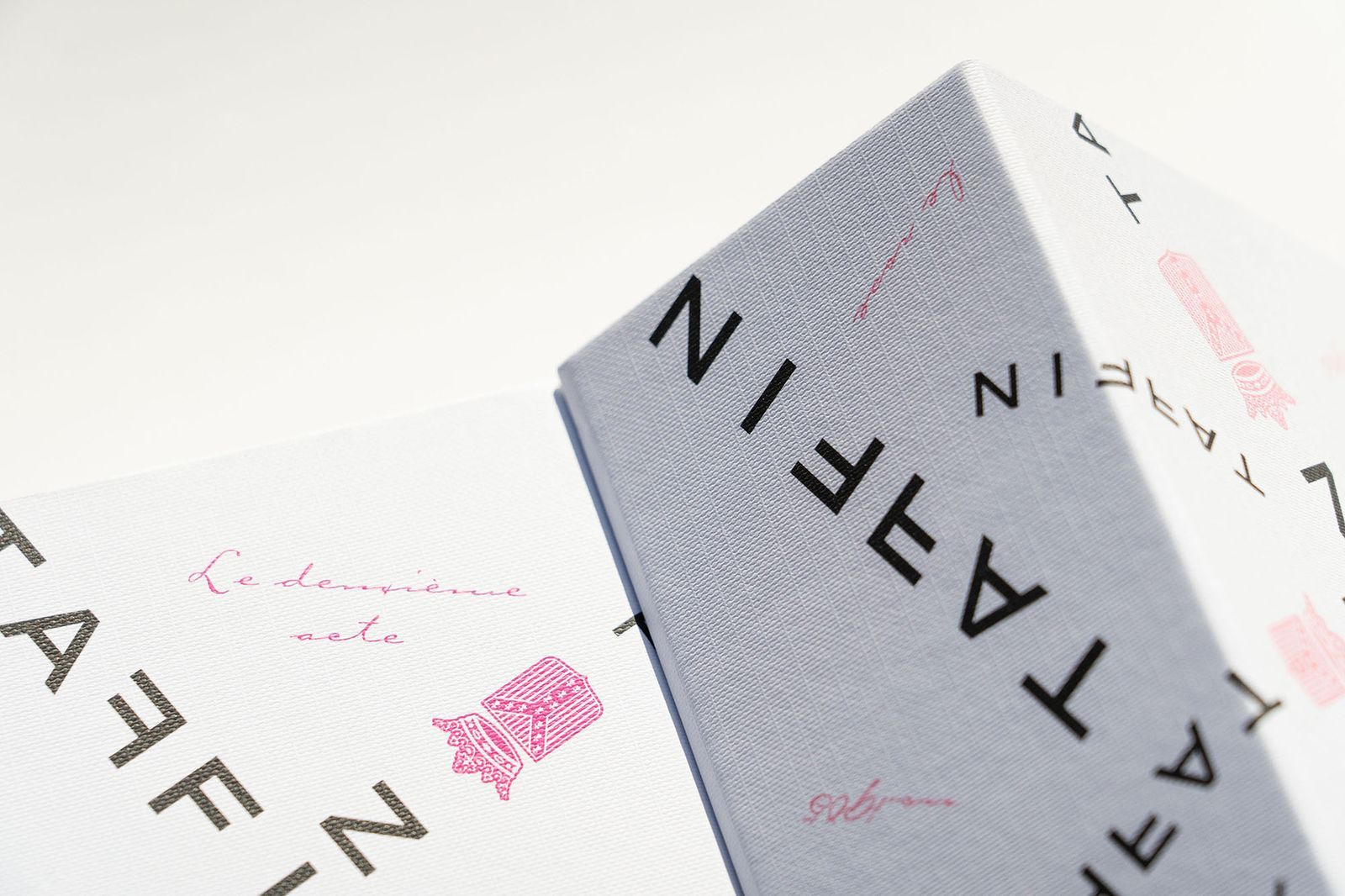 Close-up of two textured boxes with Taffin branding and pink decorative script and motifs.