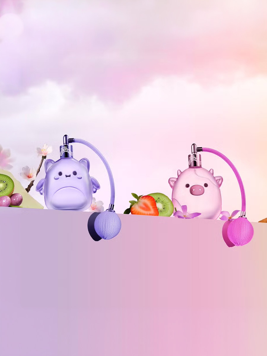 Two cute perfume atomizers shaped like purple dragon and pink pig with fruits and flowers background.