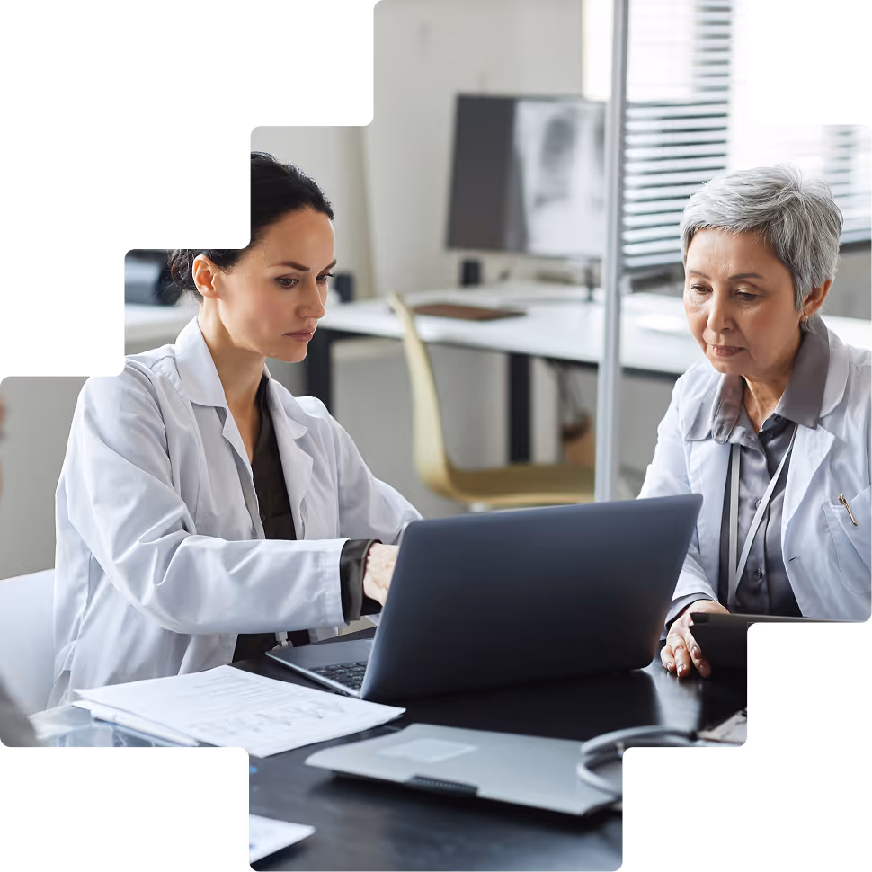Two clinicians reviewing patient records on laptop