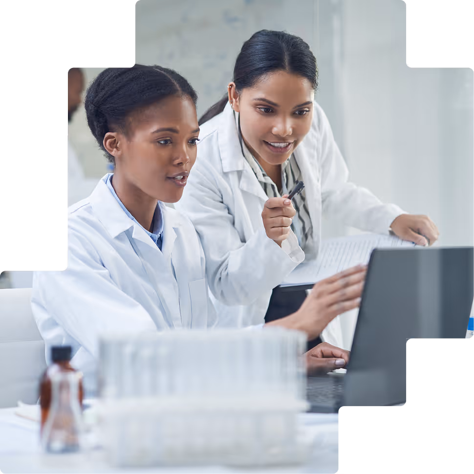 Two female researchers collaborating at laptop in lab