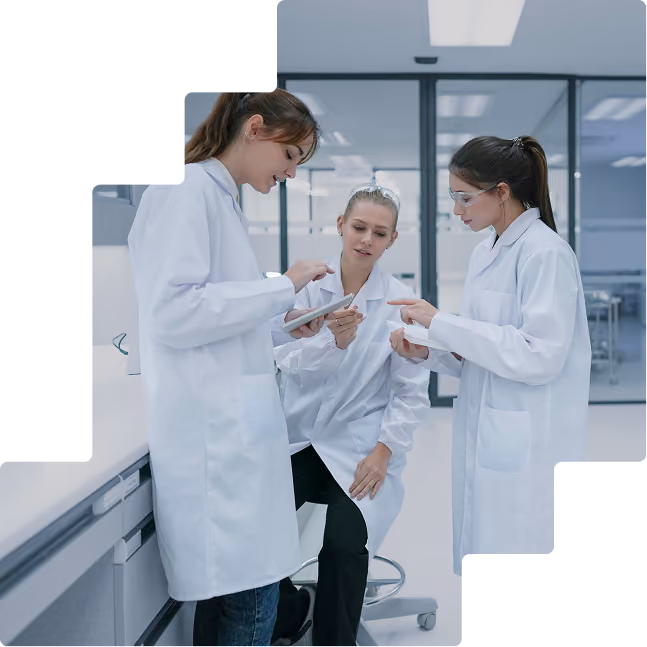 Three women in lab coats: Clinical research team reviewing study data together in a laboratory