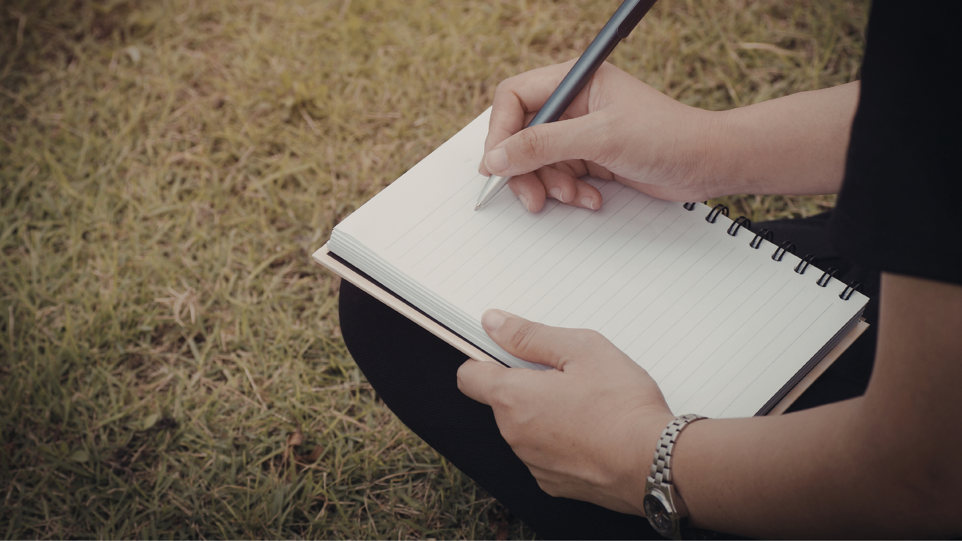 Open field notebook with bird sketches and notes next to binoculars in the field