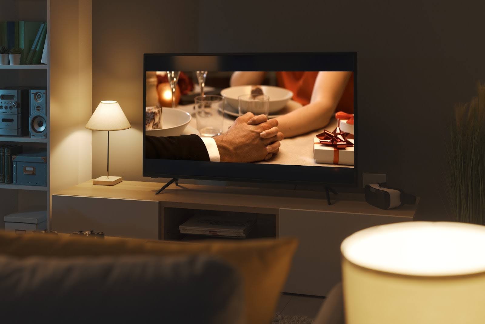 La pantalla del televisor muestra una película romántica de una pareja tomados de la mano sobre una caja de regalo | 7 películas como el Diario de una pasión