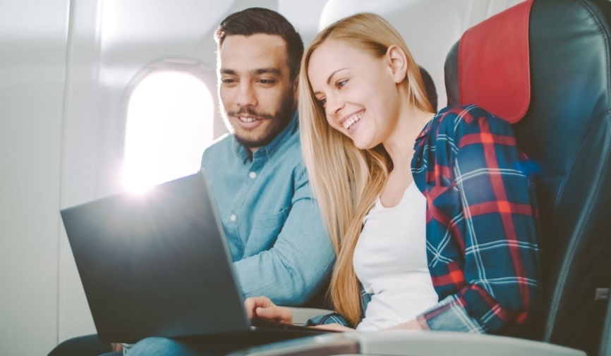 Pareja viendo una película en una computadora portátil en un avión | Las mejores películas para ver en un avión