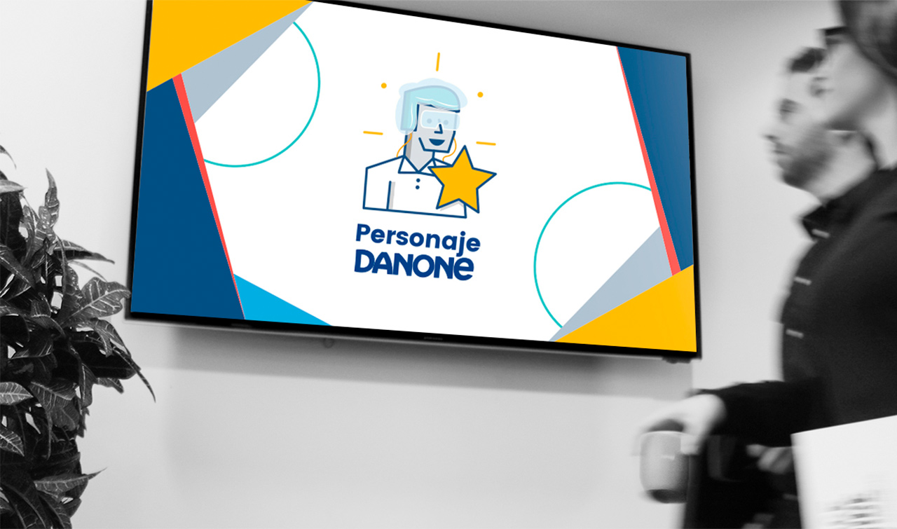 Two blurred people stand near a TV screen showing a graphic with text 'Personaje Danone'.