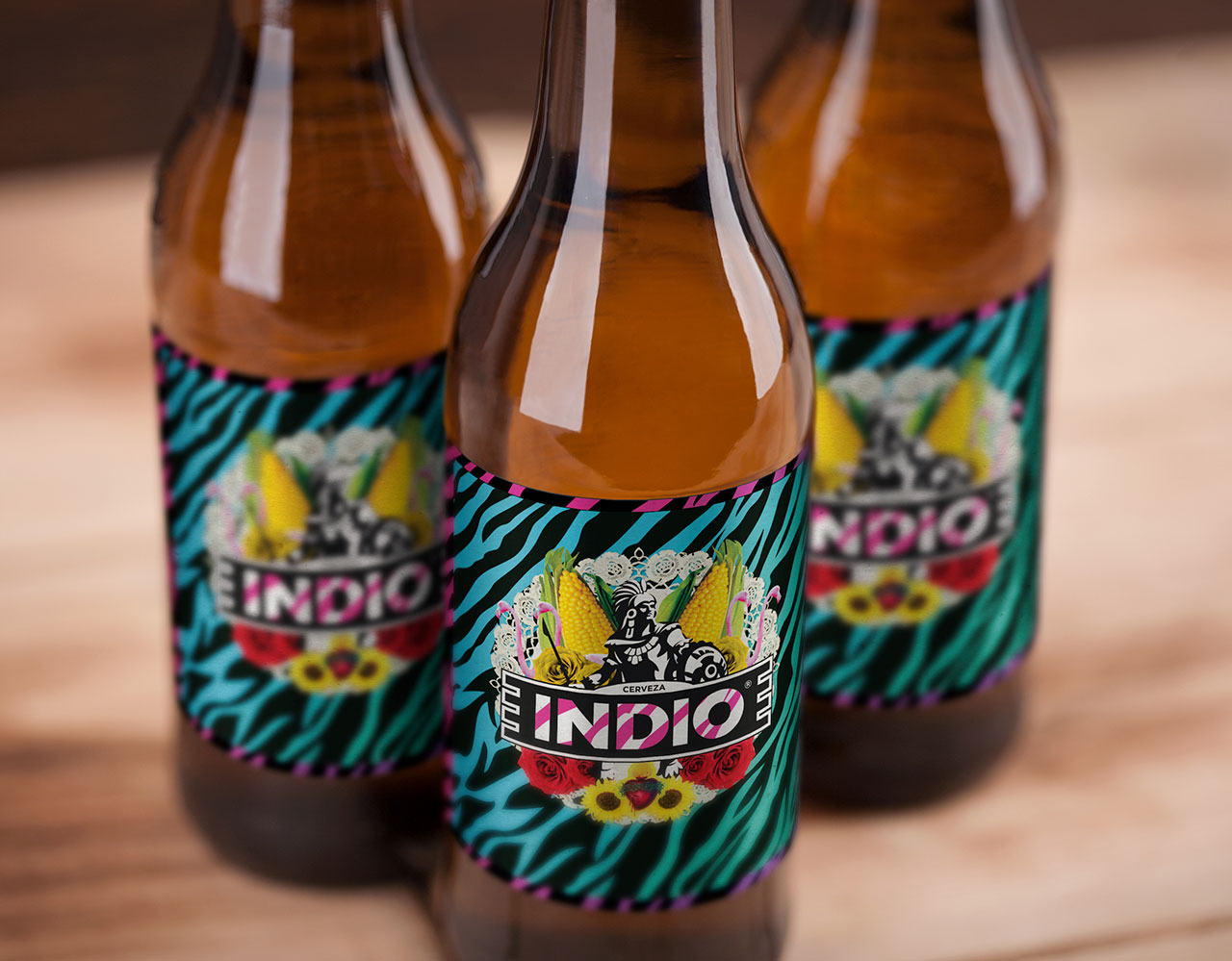 Three Indio beer bottles clustered together on a wood surface, close-up view of the label design.