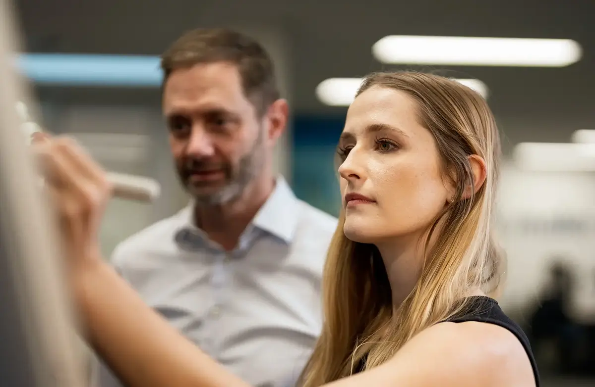 Two professionals reviewing work together in an office setting.
