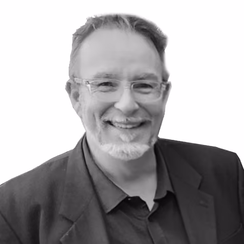 Smiling man with glasses and short hair wearing a dark jacket and shirt on white background.
