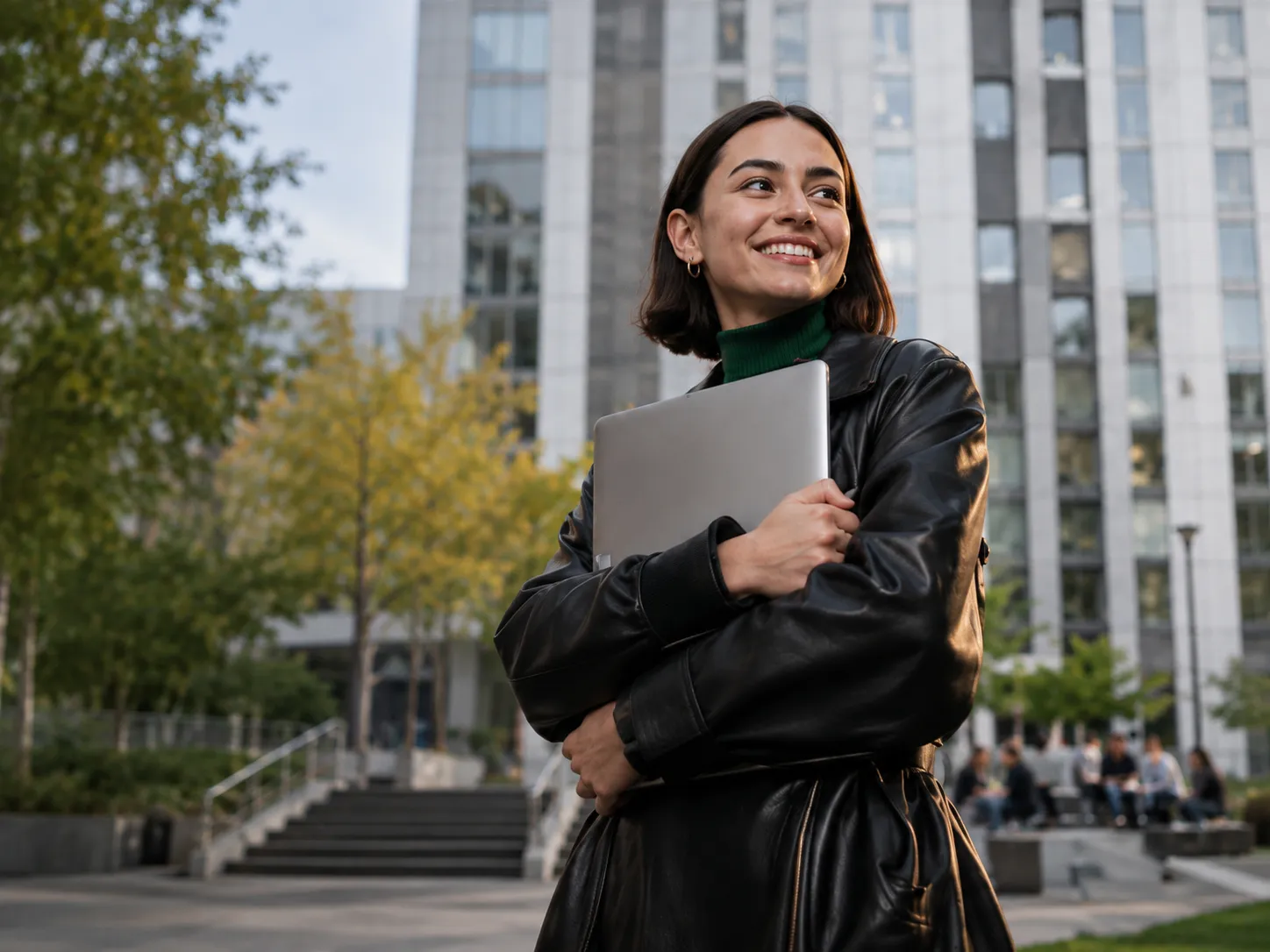 Estudiante universitaria sonriendo con un portátil en el campus