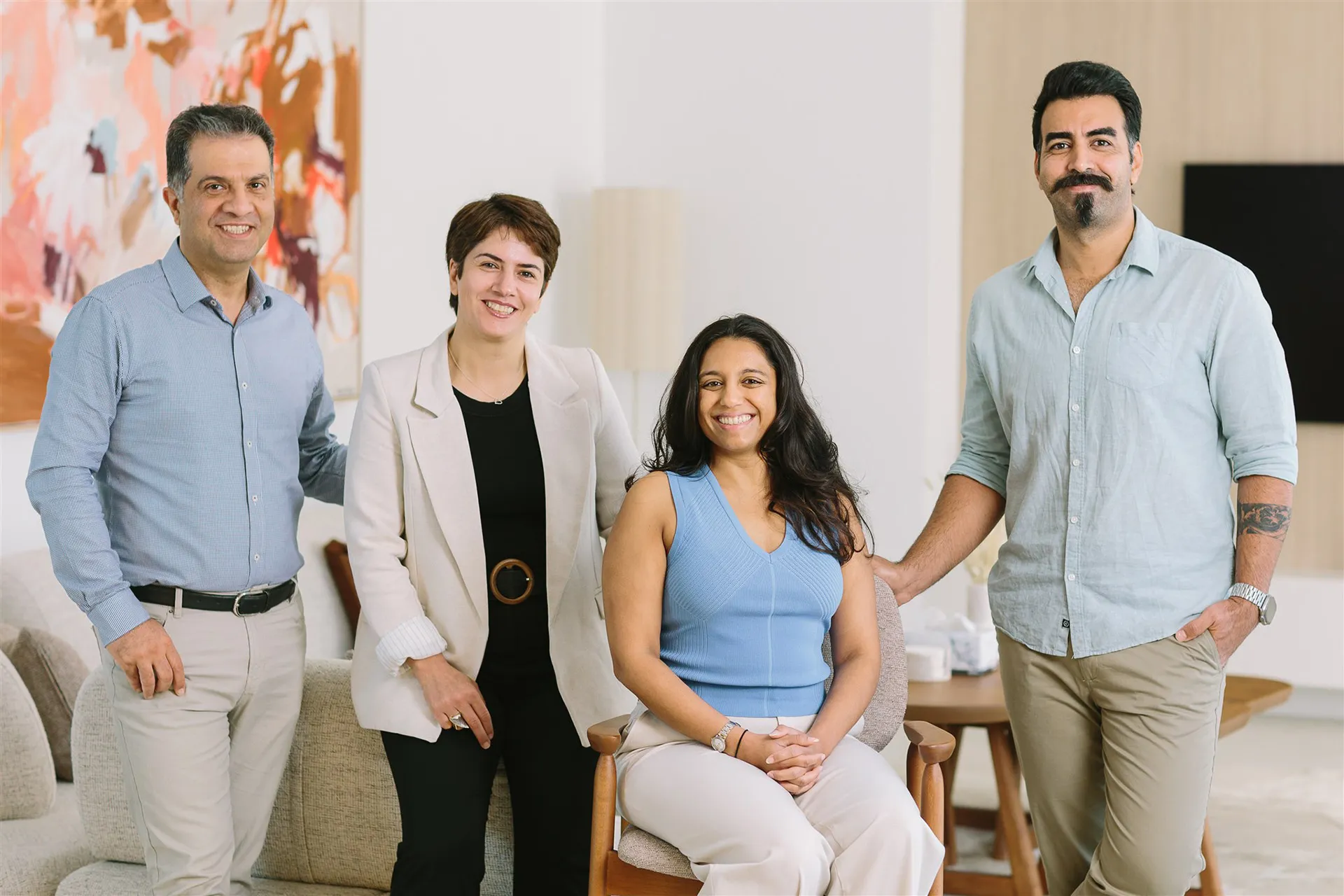 The PlanCo Homes team gathered together in a modern living room, including founders Paris and Masoud