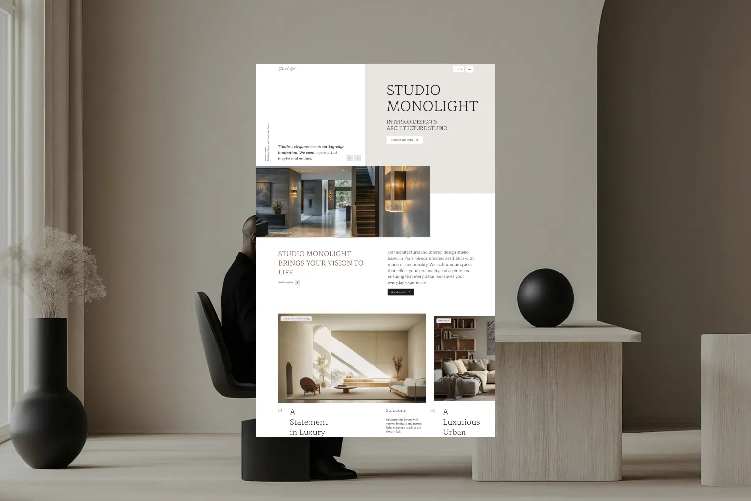 Modern interior scene with a person sitting on a black chair against a beige wall, beside a light wood table with a black spherical decor piece and a black vase with dried plants, overlaid with a website design for Studio Monolight focusing on interior design and architecture featuring elegant, minimalist spaces and neutral tones.