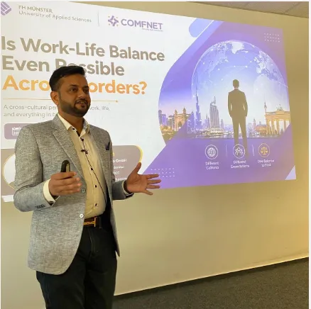 Man in a gray blazer giving a presentation about work-life balance across borders with a projector screen.