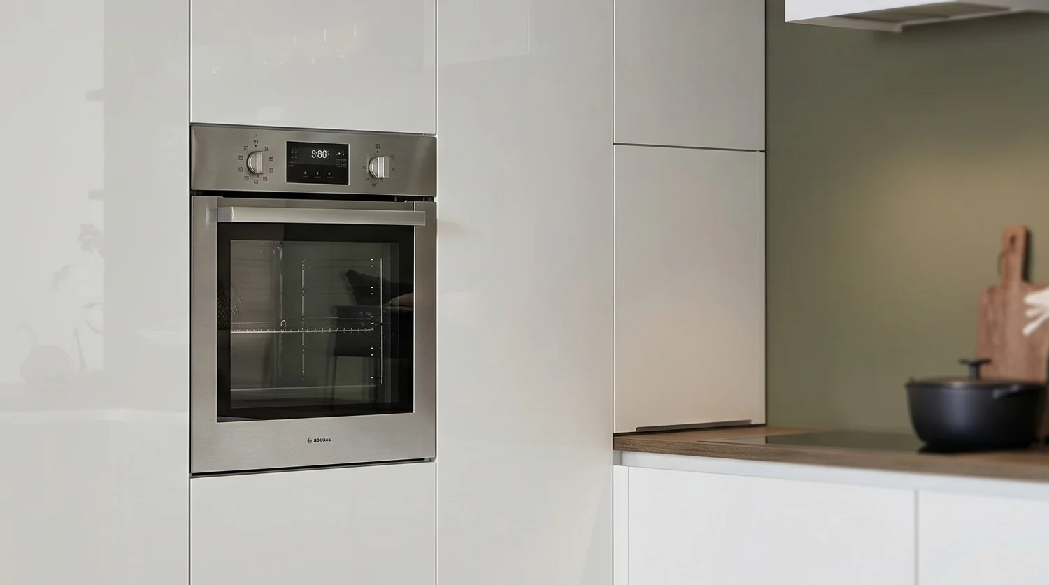 Einbau-Backofen in weißer Küchenhochschrankwand neben Arbeitszeile.