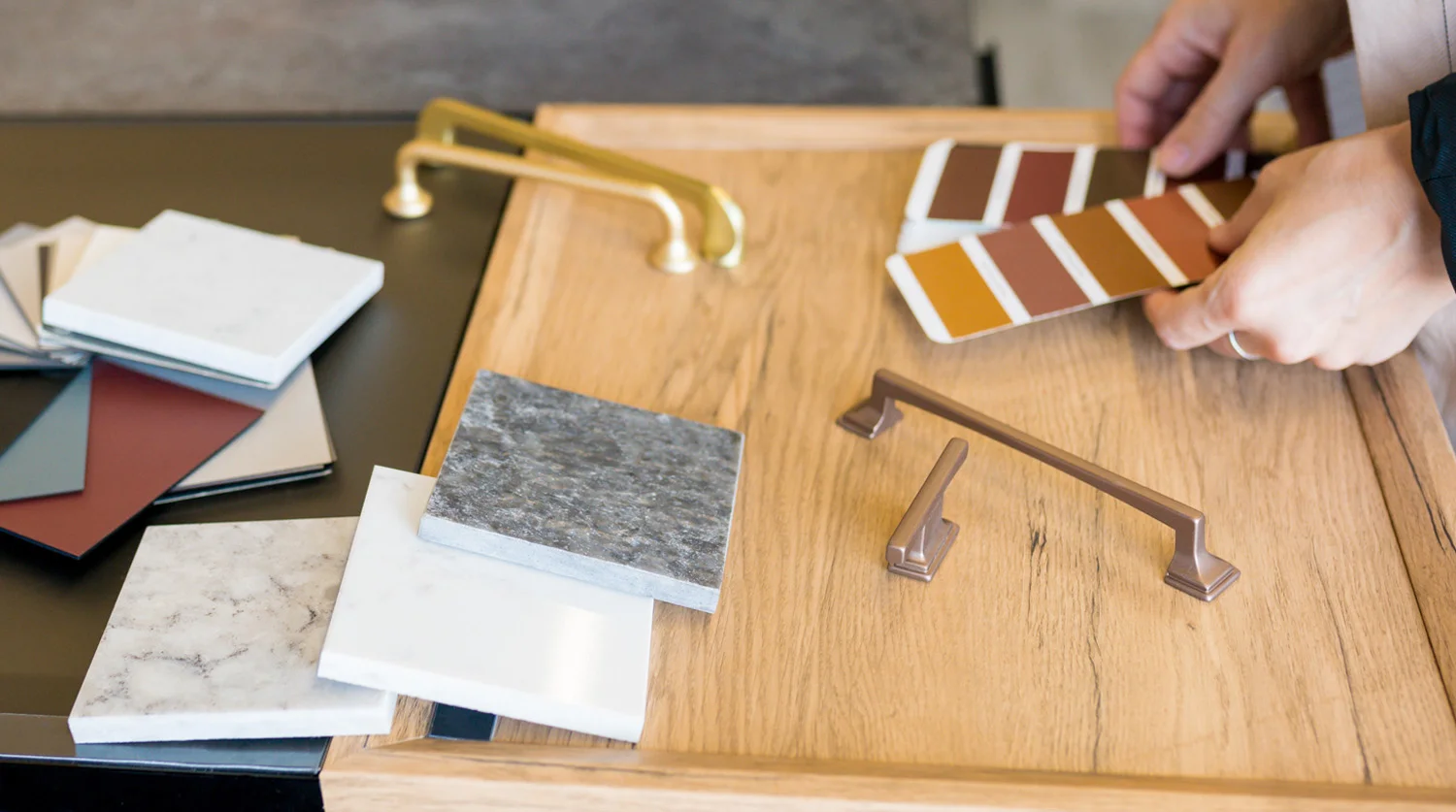 Auswahl von Materialmustern, Griffen und Farbfächer zur Küchenplanung auf Holztisch.